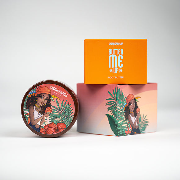 Round Butter Me Up body butter container with tropical girl illustration next to matching orange packaging.