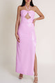 Woman in bright pink dress with halter neck and side slit, showing sophisticated style from Macao collection.