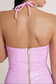 Close-up of woman in vibrant pink dress showcasing the elegant halter tie around the neck, with gold zipper and open back adding a refined finish.