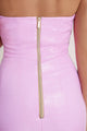 Close-up of woman in vibrant pink halter neck dress with visible back and gold zipper, highlighting refined elegance from the Macao collection.