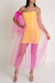 Woman wearing a yellow strapless dress with pink tulle overlay against a white background.