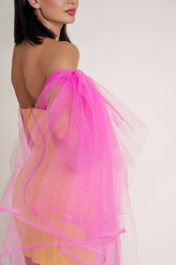 Woman in bright yellow Casa Di Campara dress with pink tulle overlay, posing with hand on hip. Elegant yellow dress.