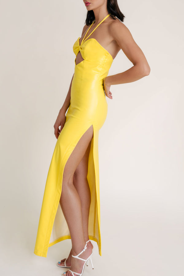 Woman wearing a Mandarin Mystique yellow gown with a high slit and white heels