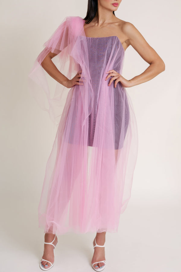 Woman wearing a black Casa Di Campara mini dress covered with pink tulle, posing in white heels.
