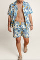 Man wearing a blue patterned shirt matching with Algarve Coast shorts on a plain background.