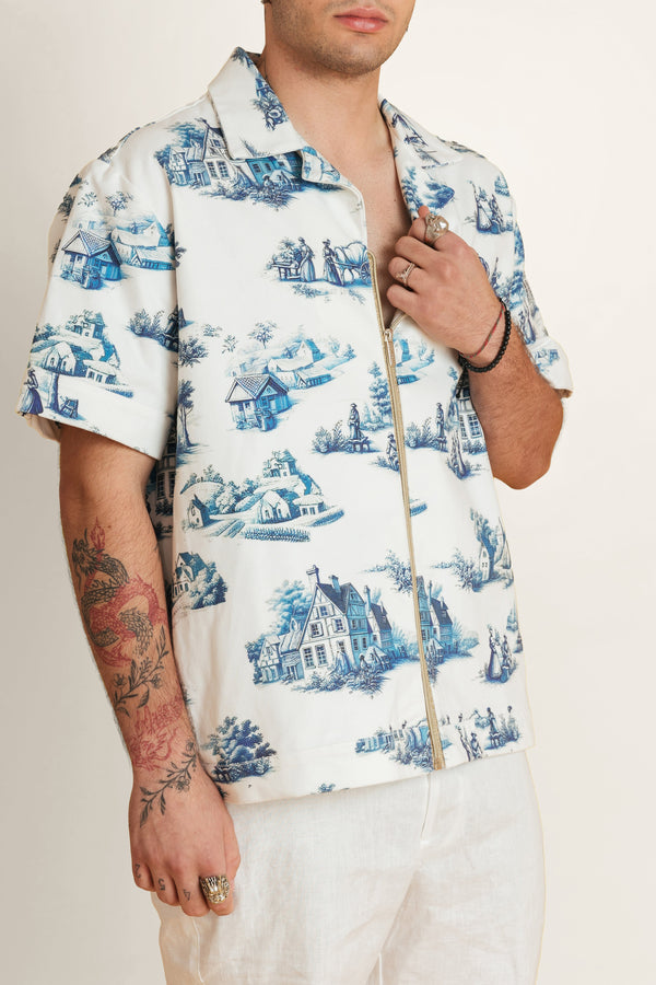 Man wearing a cotton white shirt with blue patterns on it and a gold zipper detail.