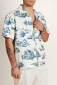 Man wearing a cotton white shirt with blue patterns on it and a gold zipper detail.