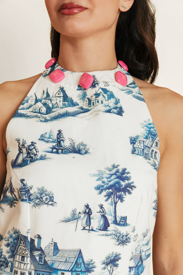 Close-up of the Lagos Azure cotton dress, highlighting the white fabric, blue print, and pink detailing around the neckline.