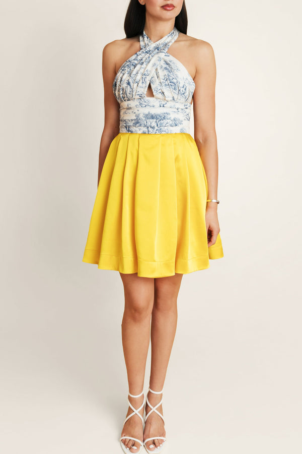 Woman in Faro Lemonade dress by Casa Di Campara, with blue-white printed top and bright yellow vegan silk skirt.