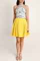 Woman in Faro Lemonade dress by Casa Di Campara, with blue-white printed top and bright yellow vegan silk skirt.