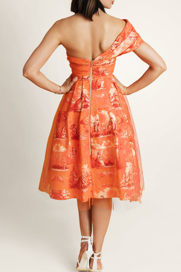 Back view of a woman in an elegant one-shoulder dress, featuring a striking golden zipper detail.