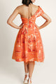 Back view of a woman in an elegant one-shoulder dress, featuring a striking golden zipper detail.