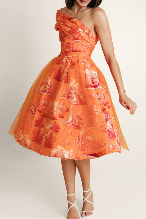 Woman in orange midi dress of thick cotton and soft tulle, with bold orange print.