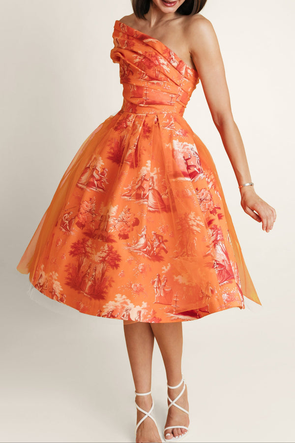 Woman in orange midi dress of thick cotton and soft tulle, with bold orange print.