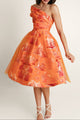 Woman in orange midi dress of thick cotton and soft tulle, with bold orange print.