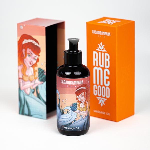 The focus is on a massage oil bottle with a pump, with the orange cap and the lower part of the box featuring a mermaid design visible in the background.