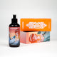 A bottle of massage oil in focus with an orange Rub Me Good product package featuring a mermaid in the background.