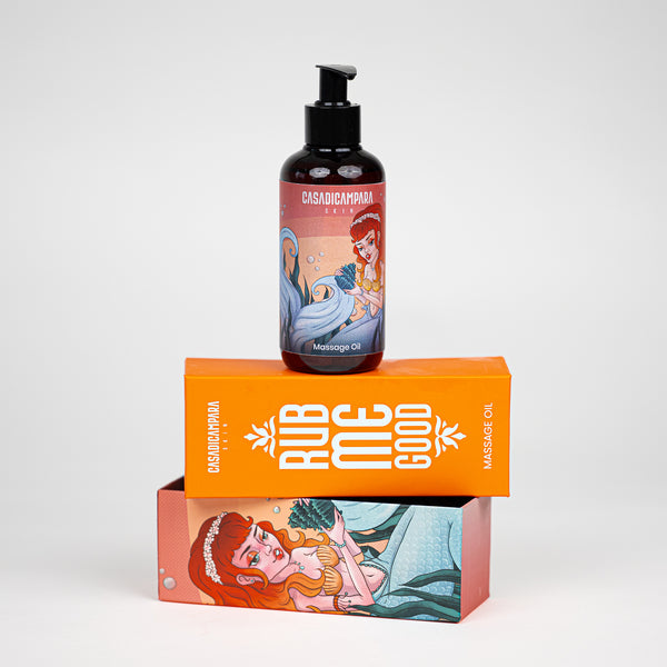 Rub Me Good massage oil bottle with mermaid illustration and pump, on top of of orange packaging box.