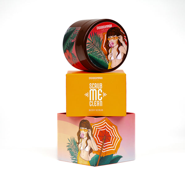 Round brown body scrub with girl illustration placed on top of orange packaging with white text, exfoliating skincare essential.