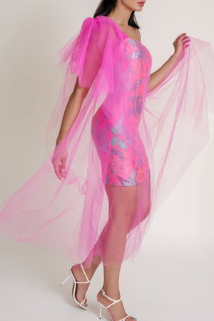 Woman wearing a pink Casa Di Campara dress with blue details, pink tulle overlay, and white heels. 
