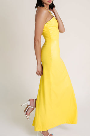 Woman posing sideways and wearing a Casa di Campara yellow dress with white heels. 