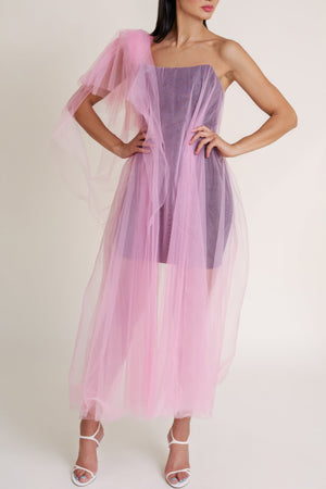 Woman wearing a black Casa Di Campara mini dress covered with pink tulle, posing in white heels.