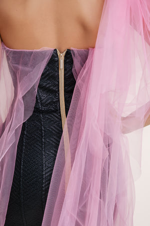 Back view of a strapless black textured dress with gold zipper, adorned with sheer pink tulle overlay for a soft, elegant touch.