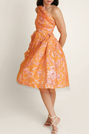 Side view of a woman in an orange-pink Sintra Magic dress with off-shoulder design, showcasing the dress in motion and its delicate floral print.